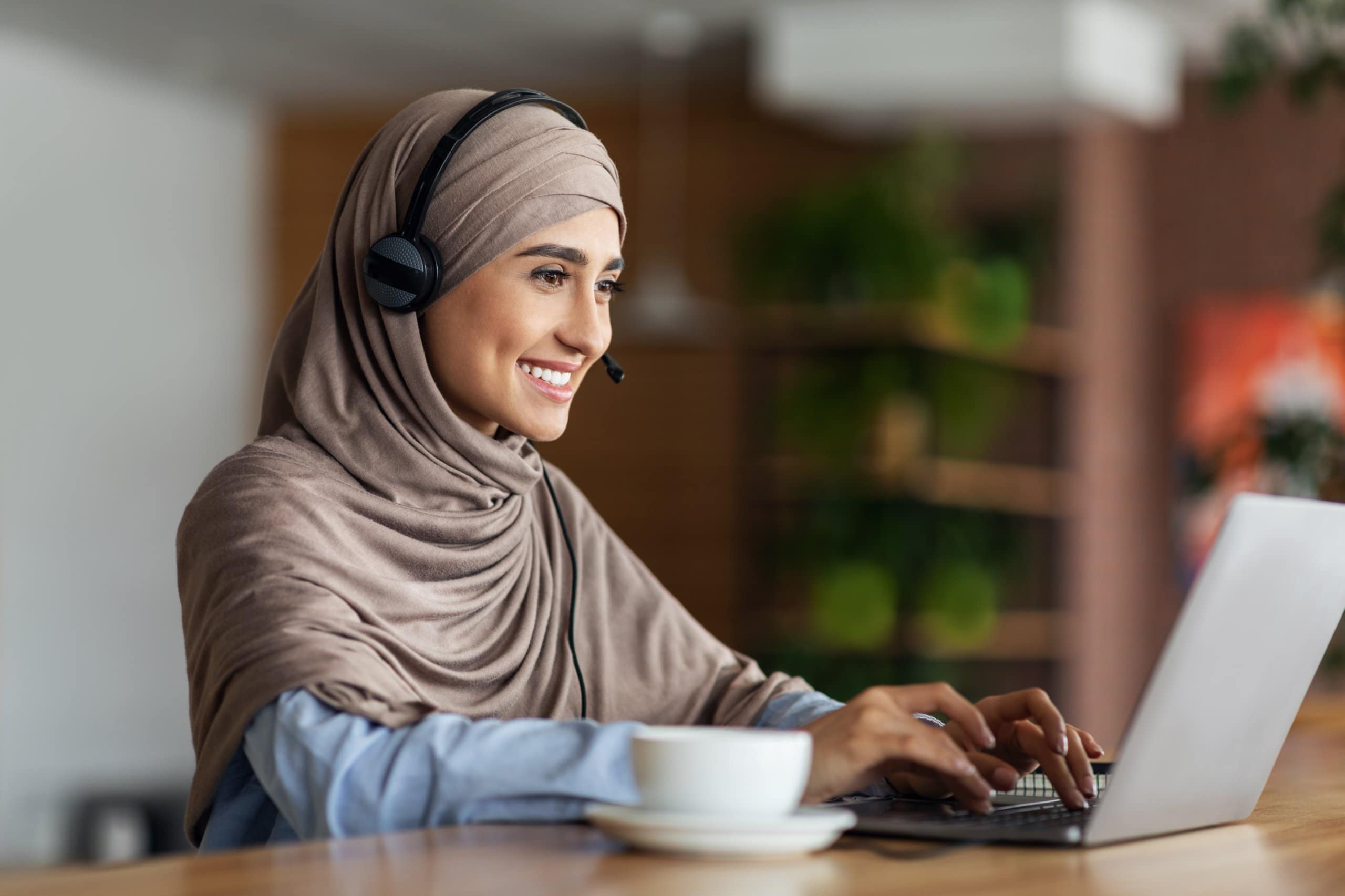 Smiling,Muslim,Girl,Studying,Online,At,Cafe,,Using,Laptop,And